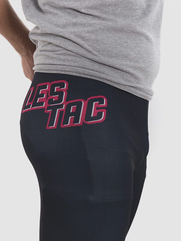 A closeup image of a male model wearing black cycling leggings with the text "les tac" printed on the right thigh area.