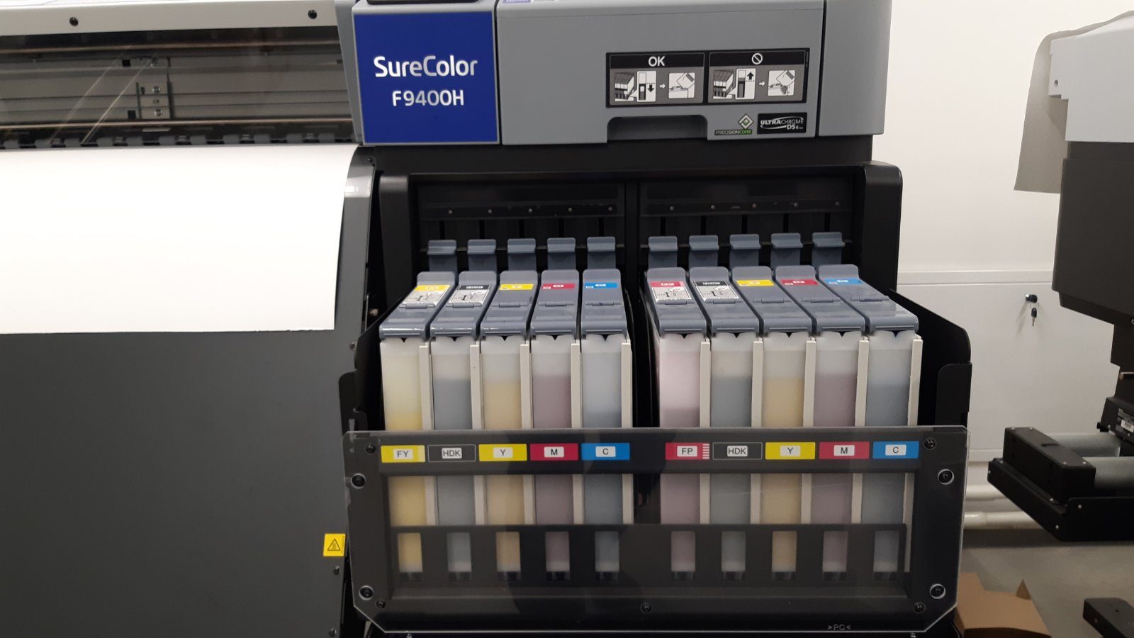 Photo of the Epson SureColor SC-F9400H dye sublimation at the FUSH clothing factory. FUSH logo is visible in the upper left corner of the photo.