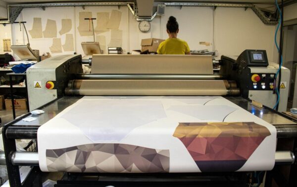 Calender heat press for sublimation printing at a clothing factory.