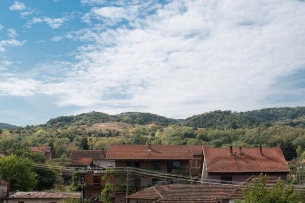 Houses at the foot of the hill and the white scattered clouds can be seen in this image.