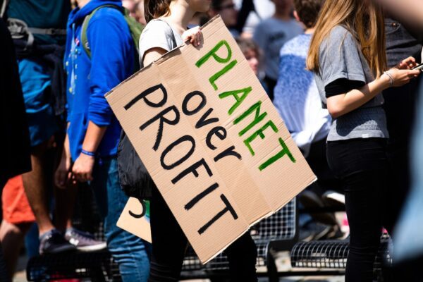 Image of a protester holding a banner saying "planet over profit".